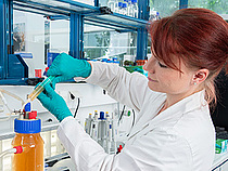 Genomische Biotechnologie Master Eine rothaarige Studentin steht im Labor und führt einen Versuch durch.